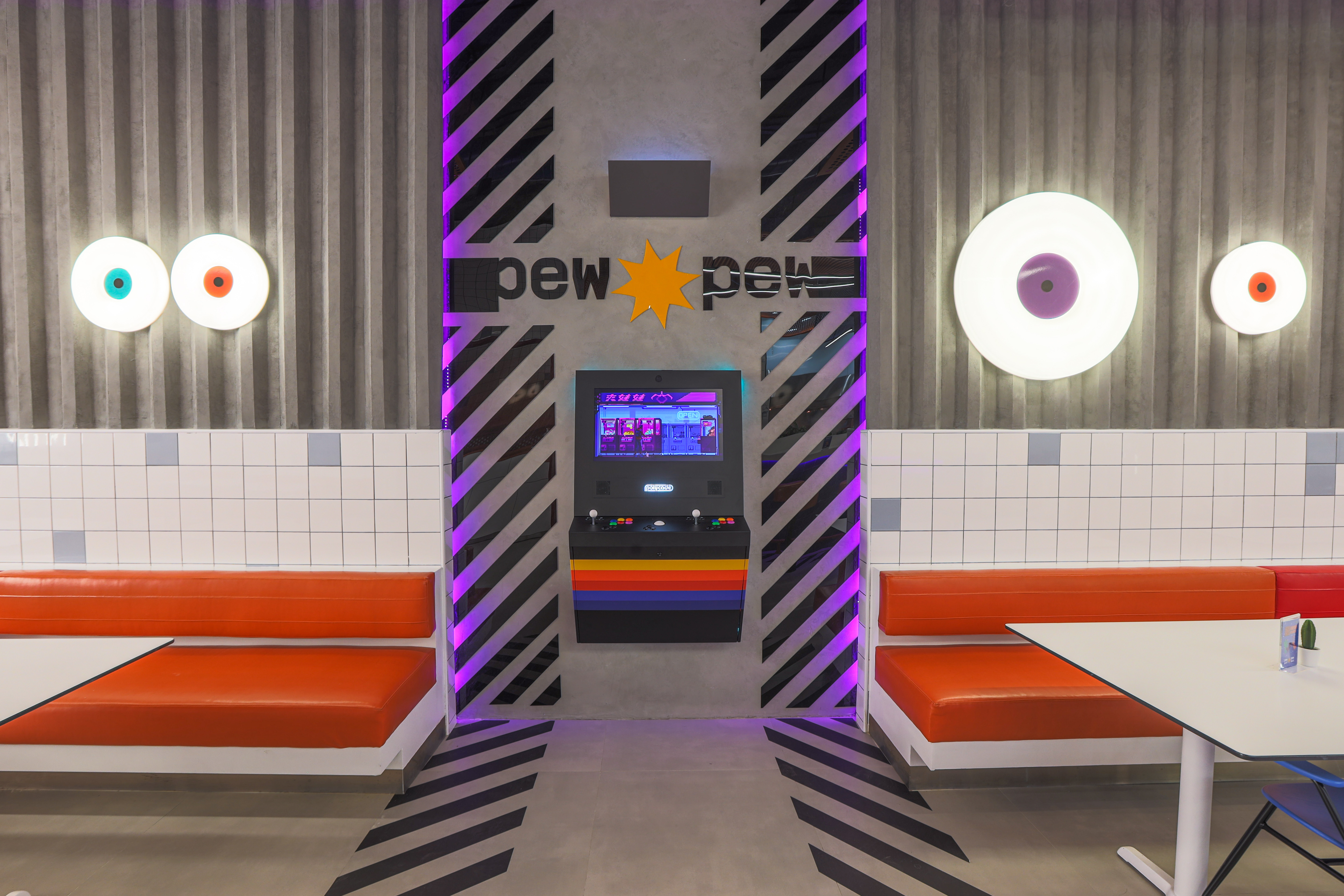 Pew Pew — full view of the bar with orange stools and purple lighting